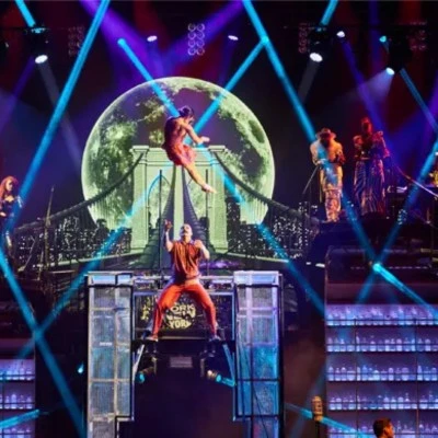 Performers on stage with aerial act and city backdrop at Mad Apple, Las Vegas.