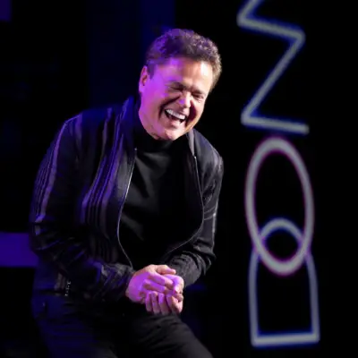 Donny Osmond laughs while on stage during a show.