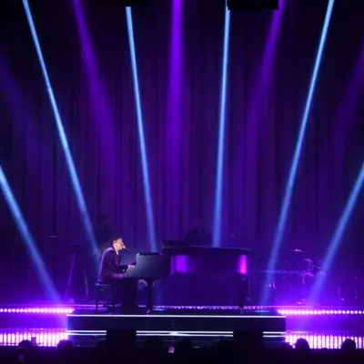 Donny Osmond plays piano on stage.