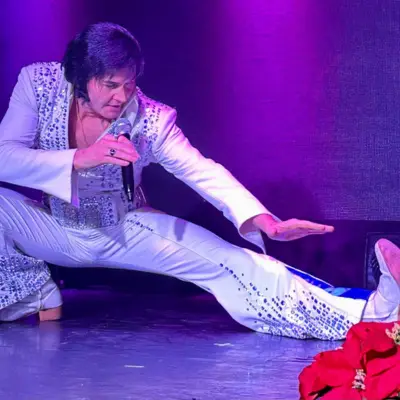 Elvis impersonator posing a gesture on stage.