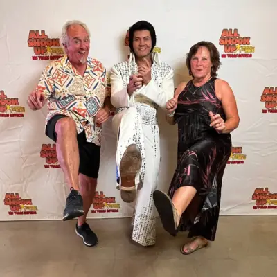 Elvis impersonator posing for a picture with the fans.