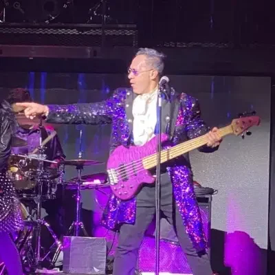 A male member of the band with his hands pointing to the crowd