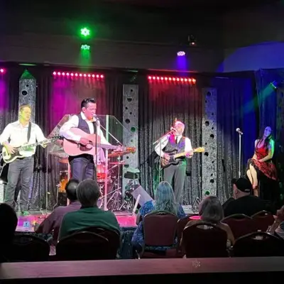 Performers from Cash After Dark singing with guitars on stage