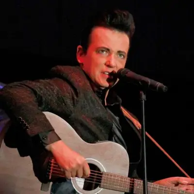 The impersonator performing with a guitar on stage