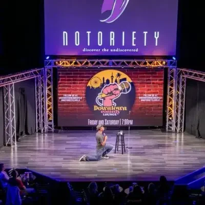 Comedian kneeling on the stage while performing his skit