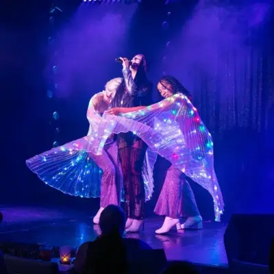 Cher impersonator/singer performing on stage alongside dancers