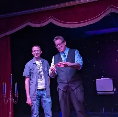 Jeff Ezell holding a dollar with audience at the Witches and Warlocks show