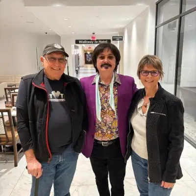One member of the tribute show posing with two fans