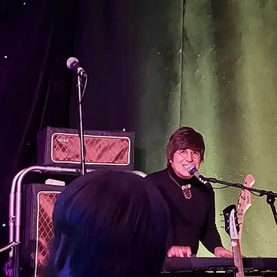 the members of the tribute show singing with a guitar