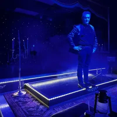 Magician standing on a smokey stage with neon lights at the Witches and Warlocks show