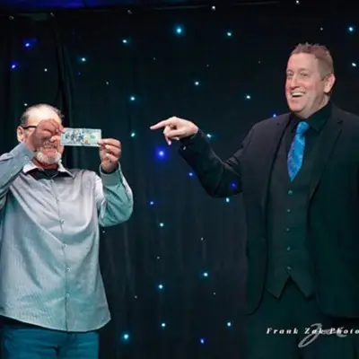 Magician pointing a finger at audience member holding a dollar at the Masters of Magic Show