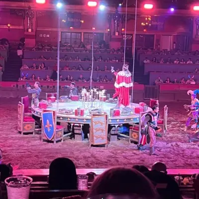 Performer dressed as King Arthur stands on the Round Table at the Tournament of Kings show