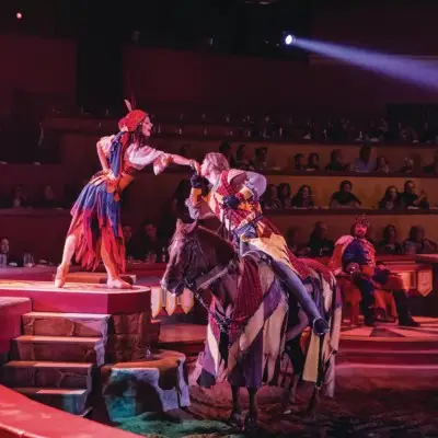 Performer in a knight’s costume kissing a maiden’s hand at the Tournament of Kings show