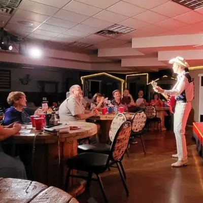 Performer in cowboy hats and boots singing with band at the Firelight Barn theater