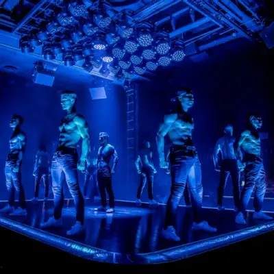 Performers posing under blue lights in Magic Mike Live in Las Vegas
