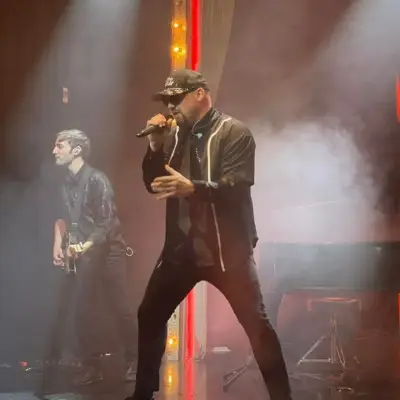 Piano Man performing energetically on stage with guitarist in the background.
