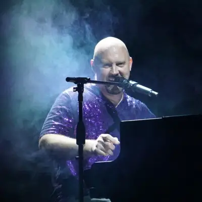 Close-up of Piano Man performer smiling while playing the piano and singing on stage.