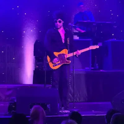 Purple Reign wearing sunglasses plays a yellow guitar on stage