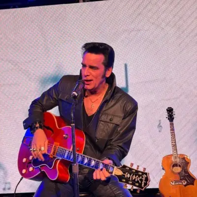 The Elvis impersonator singing while playing the guitar