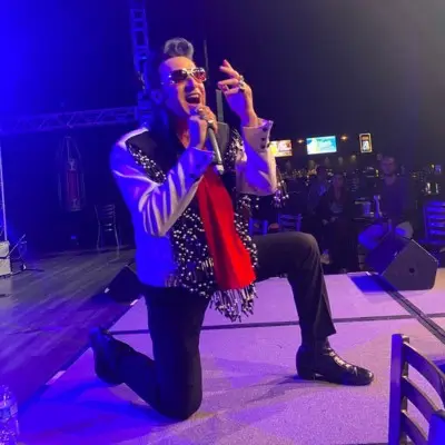 The Elvis impersonator performing while on his knees