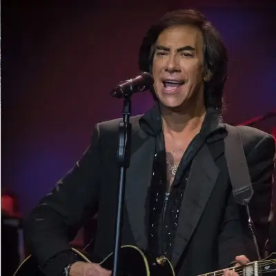The impersonator performing with a guitar on stage at the OYO Hotel and Casino