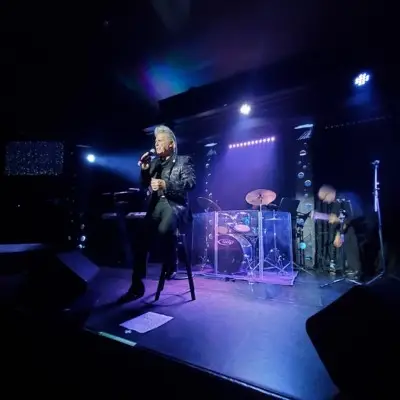 The artist from Frankie Valli Tribute show singing on stage with lights falling on him