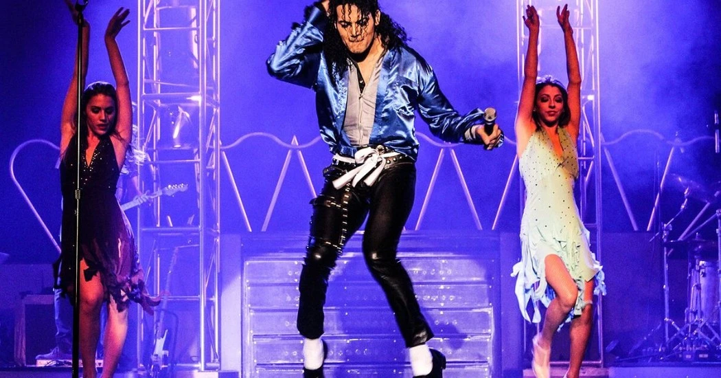 MJ Live performer striking a signature Michael Jackson pose in full costume on stage.